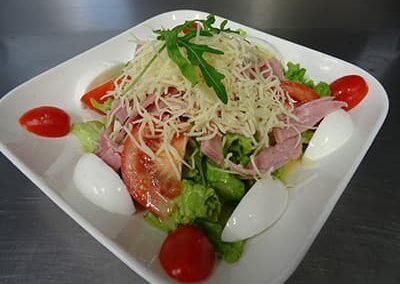 Assiette blanche avec salade, oeuf dur, tomate, jambon, recette salade du chef du restaurant "Les délices du Cotentin" à Sainte mère.